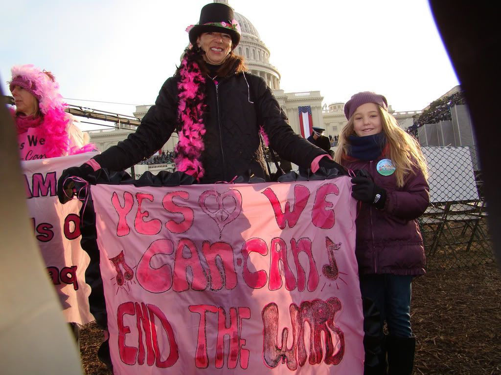 CODEPINK sings &quot;Yes We Can-Can End War&quot;, CODEPINK member Desiree Fairooz holds up a sign at Obama's inauguration.  CODEPINK members dressed up in skirts and boas to dance can-cans at the inauguration and outside several of the evenings balls with the message "Yes, we can-can end the wars."
